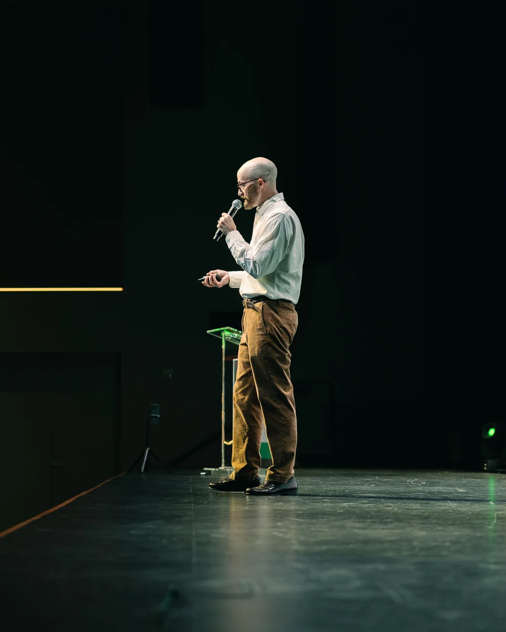 Todd Larsen speaking on stage with a microphone and presentation remote